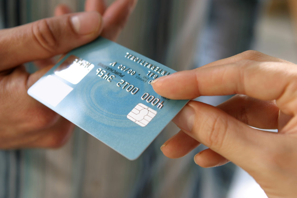 Hand passing a payment card (N.B. Mocked Up Details*)